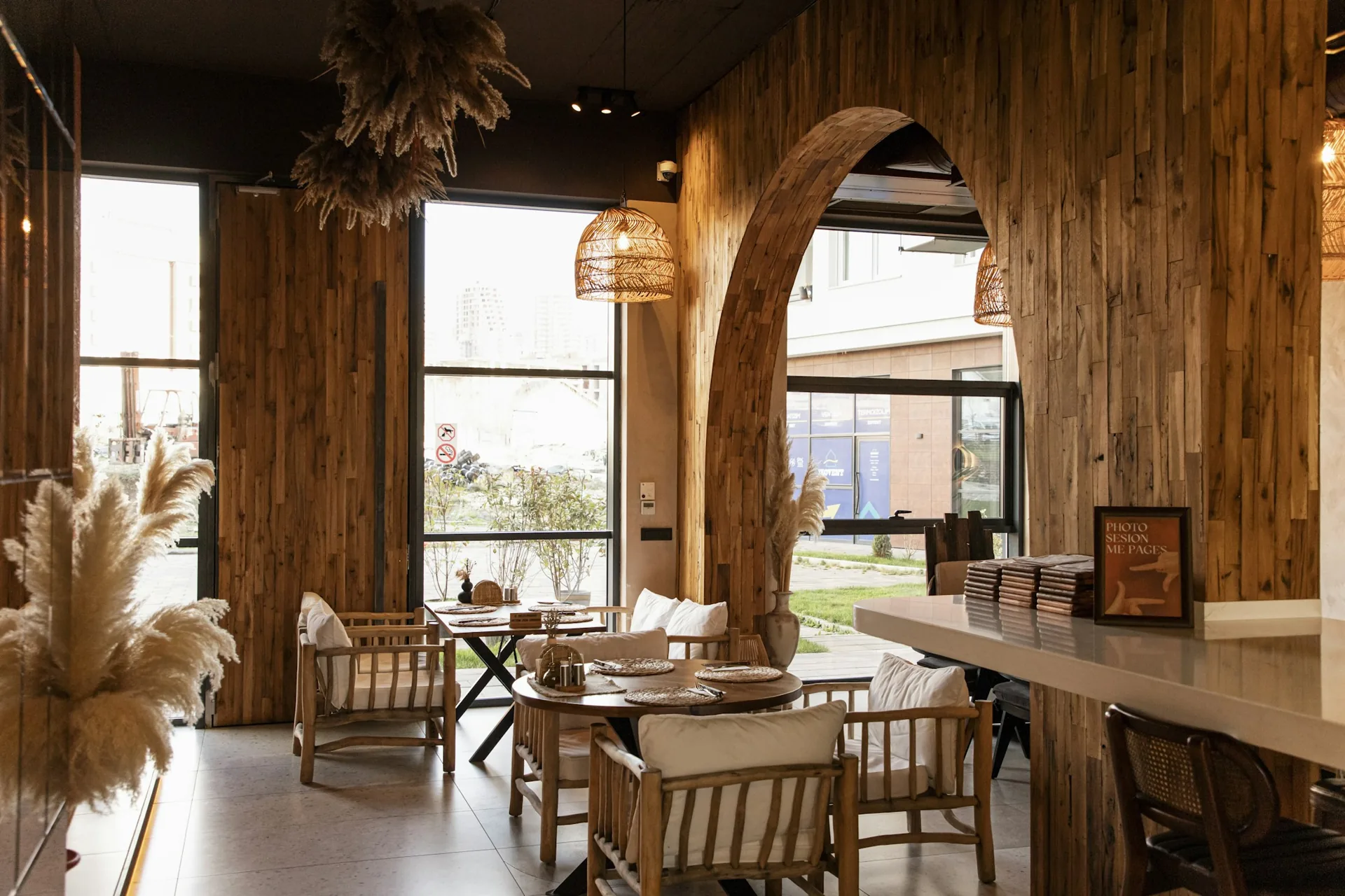 A sunlit café interior with wooden arches, chairs and inviting tables