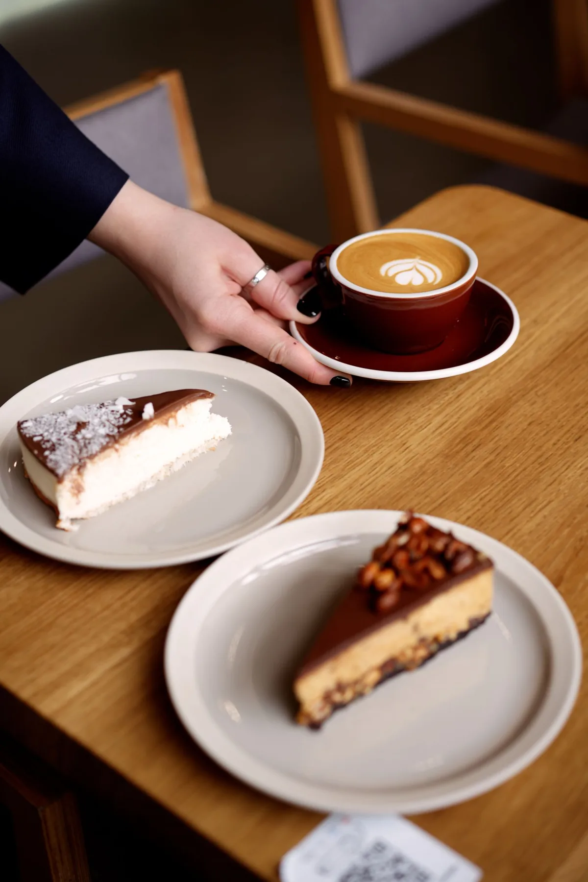 Two slices of cheesecake and a cappuccino on a wooden table