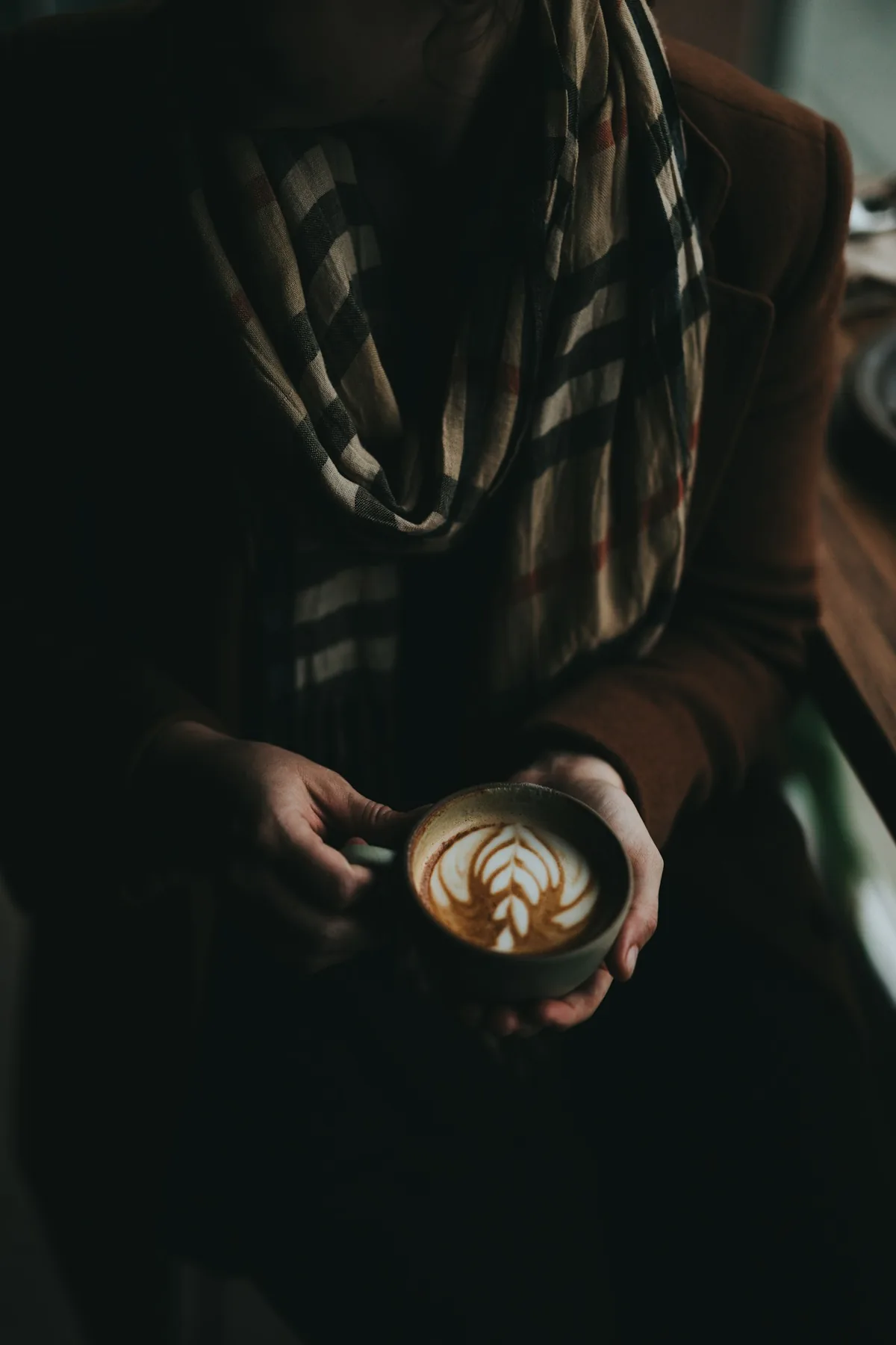 A warm cup of coffee with latte art held in two hands